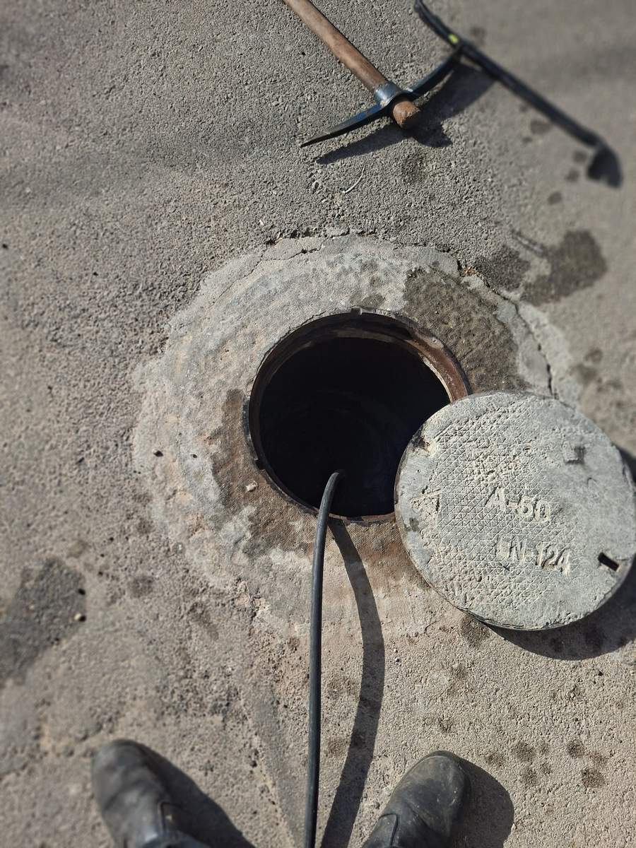 שוחת ביוב ראשית פתוחה עם מכסה בצד וקפיץ מוכן לעבודה